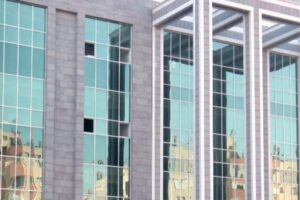 Nowoczesny budynek z turkusowymi oknami szklanymi odbijającymi krajobrazy miasta - Metamar