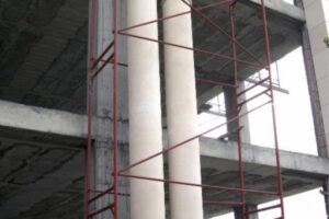 Budowa betonowa z czerwonymi rusztowaniami i białą kolumną - Metamar