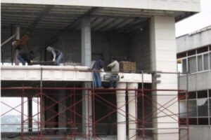 Pracownicy na rusztowaniu przy budynku w budowie - Metamar