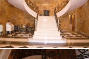 Eleganckie schody z białym biegiem, złote ściany, metalowe poręcze - Metamar