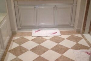 Łazienka z szachownicową posadzką beżowo-białą, białymi szafkami i białymi ręcznikami - Metamar