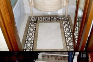 Łazienka z białą umywalką, drewnianymi drzwiami i płytkami z geometrycznym wzorem.