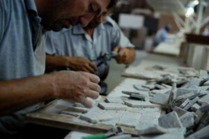 Mężczyzna pracuje przy stole, rzeźbi w kamieniu narzędziem - Metamar