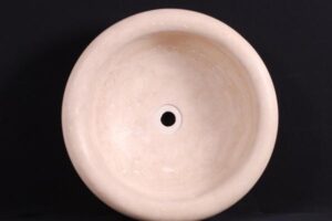 Beżowa okrągła umywalka z otworem odpływowym na czarnym tle - Metamar