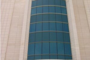 Nowoczesny budynek z zaokrąglonymi niebieskimi oknami i beżową ścianą - Metamar