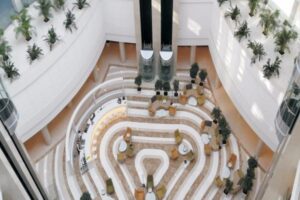 Widok z góry na nowoczesne wnętrze z spiralnymi półkami, roślinami i meblami.