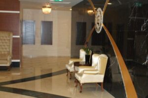 Nowoczesny hol z białymi fotelami i czarno-złotą dekoracją ścienną. - Metamar