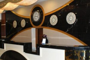 Wnętrze z czarnymi ścianami, złotymi akcentami i pięcioma zegarami ściennymi.
