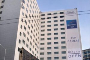 Hotel Novotel, budynek biały, napis na elewacji, ulica miejska - Metamar