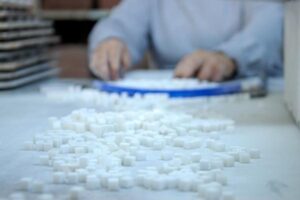 Osoby sortuje białe kostki cukru na stole.