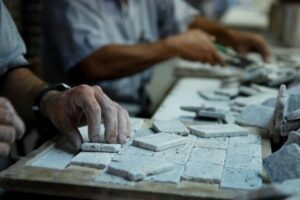 Ręce pracownika układające kafelki, warsztat budowlany - Metamar