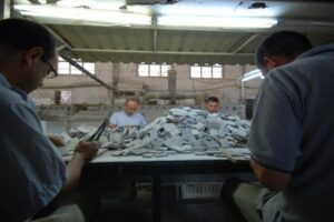 Pracownicy sortują materiały na stole w hali produkcyjnej - Metamar