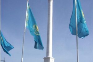 Turkusowe flagi Kazachstanu przy białym słupie na tle nieba - Metamar