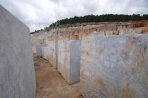 Kamienny łom z wydobywanymi blokami marmuru i lasem w tle - Metamar