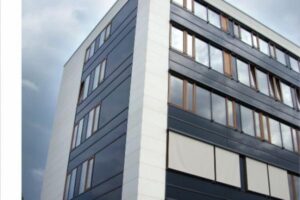 Nowoczesny budynek mieszkalny z szarymi fasadami i oknamis drewnianymi ramkami. - Metamar