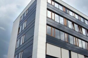 Nowoczesny budynek mieszkalny, biały i szary, wielokondygnacyjny z regularnymi oknami.