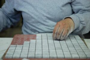 Osoba w szarej bluzie wskazuje palcem na siatkę kartkę papieru - Metamar