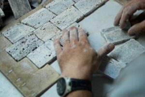 Ręce pracownika układające białe płytki ceglane - Metamar