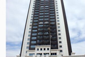 Wysoki blok mieszkalny z białą i czarną fasadą, regularnym układem okien — Metamar