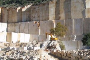 Koparka przy betonowej ścianie, gruzy i kamienie - Metamar