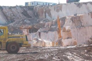 Kamieniołom z żółtą kopiarką i blokami marmuru.