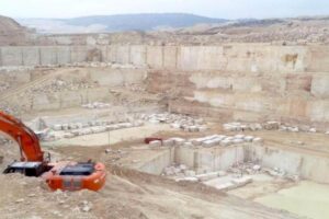 Kamieniołom z czerwoną kopiarką i betonowymi blokami