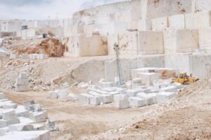 Kamieniołom z białymi blokami kamienia i sprzętem budowlanym.