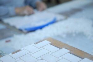 Białe płytki ułożone na drewnianym tle podczas pracy budowlanej - Metamar