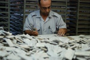 Mężczyzna w mundurze pracuje przy stole z artefaktami ceramicznymi. Metamar