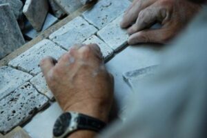 Dłonie pracownika układające cegłę podczas prac budowlanych - Metamar