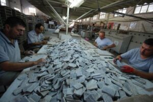 Pracownicy sortują kawałki materiału na dużym stole w hali przemysłowej - Metamar