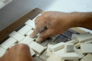 Ręka montująca białe przełączniki elektryczne na drewnianej liście.