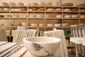 Biała ceramiczna miska na stole, półki z naczyniami w tle - Metamar